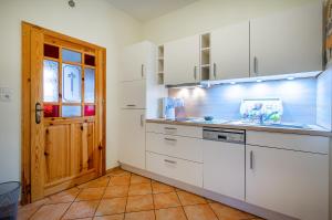 a kitchen with white cabinets and a wooden door at Gulfhof Butendiek - Ferienapartments in Neuharlingersiel