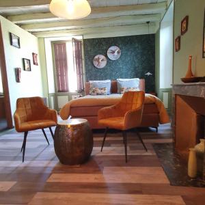 1 dormitorio con 1 cama y 2 sillas de color naranja en Maison Fossemagne, en Melle