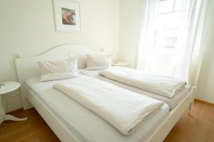 two beds in a white room with a window at Villa Hubertus Enzian in Kirchbach