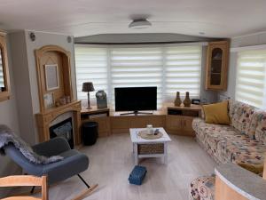 een woonkamer met een bank en een televisie bij RBR 1023 - Beach Resort Kamperland in Kamperland