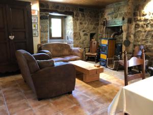 uma sala de estar cheia de mobiliário e uma parede de pedra em Maison Coquelicot em Chanéac