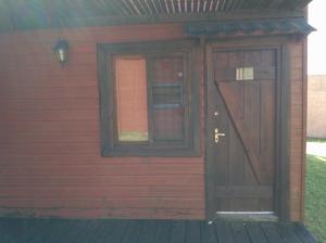 una puerta y una ventana en el lateral de una casa roja en Complejo La Pausa, en Punta del Diablo