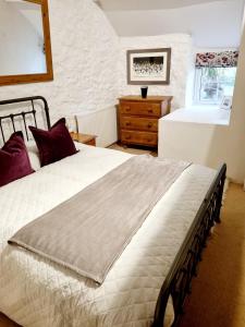 a bedroom with a large white bed and a dresser at Mayrose Cottage, Charming Cornish Cottage for the perfect escape... in Camelford