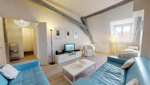 a living room with a blue couch and a tv at Tel un songe blanc in Colmar