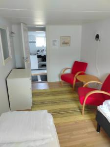 a living room with red chairs and a kitchen at Kvarngården Natur Resort in Byxelkrok