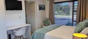 a bedroom with a bed and a television and a window at Mossel 11 Studio in Bloubergstrand