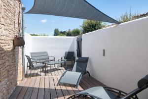 un patio avec des chaises et des tables sur un mur blanc dans l'établissement Elégance Suites Hôtel, au Bois-Plage-en-Ré