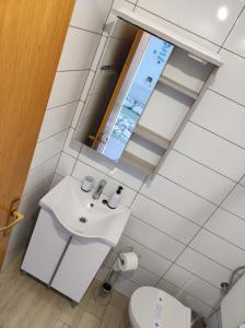ein weißes Badezimmer mit einem Waschbecken und einem Spiegel in der Unterkunft Apartmani Anđela Kordić in Rab