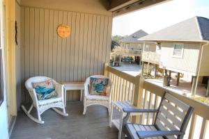 un porche con 2 sillas, una mesa y un reloj en Guest Cottage 30G, en Myrtle Beach