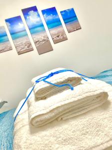 a bed with towels and pictures on the wall at Appartamento Riflessi sul mare in Gaeta