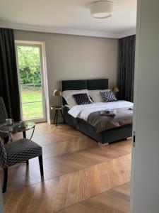 1 dormitorio con cama, ventana y silla en Kraków Green Hill Luxury Apartment, en Balice