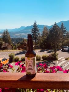 a bottle of beer sitting on a wooden fence with flowers at La bagatelle in Saint-Michel-de-Chaillol