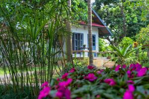 ein kleines Haus mit rosa Blumen davor in der Unterkunft SukSanti CoLiving and Vacation in Chiang Rai