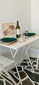 una mesa blanca con una botella de vino y una copa en Sing and Blossom Accommodation en Mykonos ciudad