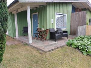 una casa verde con patio arredato con tavolo e sedie di Kvarngården i Torp a Byxelkrok