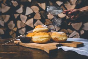 a person sprinkling powdered sugar on rolls on a cutting board at Apartma pri Boštjanu in Škofja Loka