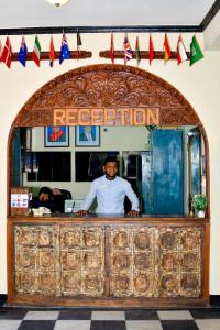Ein Mann, der hinter einem Tresen in einem Restaurant steht. in der Unterkunft Forodhani Park Hotel in Zanzibar City