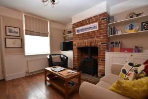 a living room with a brick fireplace and a chair at Daisy Tatham Cottage in Rye