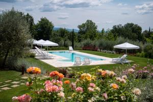 a pool in a garden with flowers and umbrellas at Villa Exclusive Fonte Ripa in Foiano della Chiana