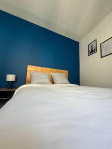 1 dormitorio con 1 cama blanca grande y pared azul en Casa Faro - Joli T2 - Hyper Centre Brive Rue Commerçante, en Brive-la-Gaillarde