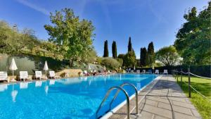 uma grande piscina com cadeiras e árvores em Borgo graziani em Città della Pieve
