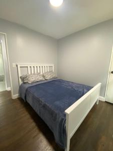 een witte slaapkamer met een bed met een blauwe deken bij 3 Bedrooms House Nassau County in Hempstead