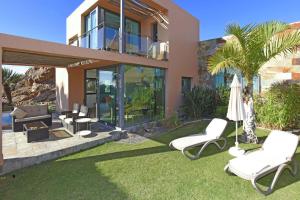 een huis met 2 ligstoelen en een parasol bij Salobre Los Lagos 27 in Maspalomas