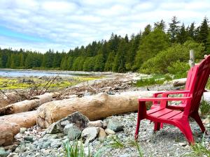 a red chair sitting on the rocks near a river at So Damn Lucky Glamping in Ucluelet