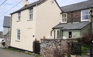 a white house with a stone wall at Trelake Cottage in Tintagel