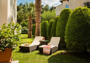 a garden with two chairs and a table and bushes at SUN RESIDENCE Exclusive Seaside Suites in Polykhrono