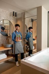 a man standing in a bathroom holding a tray ofiments at Hotel San Marco in Cattolica
