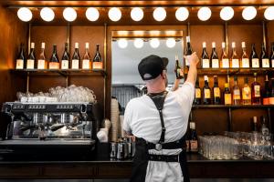 a bartender holding up bottles of wine in a bar at Backstage Hotel - an Atlas Boutique Hotel in Tel Aviv