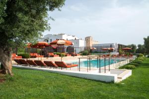 a swimming pool with chairs and umbrellas next to a pool at Masseria Santo Scalone in Ostuni