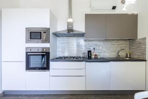 uma cozinha com armários brancos e um forno com placa de fogão em Sanremo Dream - Casa Camilla em Sanremo