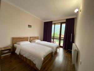 a bedroom with two beds and a large window at Cottage Kesane in Stepantsminda