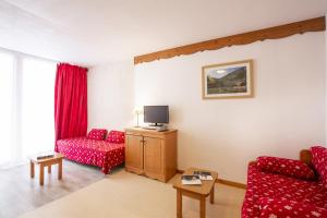 uma sala de estar com duas cadeiras vermelhas e uma televisão em Les Balcons PROCHE PARC NATIONAL VANOISE studios em Termignon