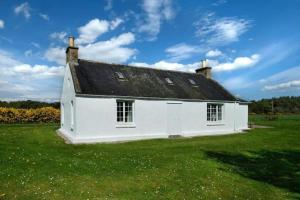 a white house with a black roof on a green field at Lower Bruntlands in Fochabers