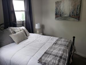 a white bed with a plaid blanket and a window at Lake View Cottage on Lake Erie in Ashtabula