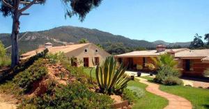 ein Haus mit einem Garten und einem Haus mit einem Berg in der Unterkunft Quinta Pedagógica da Samoqueirinha - Duna Parque Group in Vila Nova de Milfontes