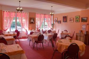 un comedor con mesas, sillas y ventanas en Le Chalet de la Foret Logis Hôtel 3 étoiles et restaurant en Vierzon