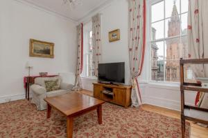 sala de estar con TV, sofá y mesa en St James Quarter 2 Bed Apartment, en Edimburgo