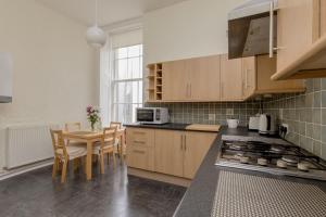 une cuisine avec des placards en bois et une table avec des chaises dans l'établissement St James Quarter 2 Bed Apartment, à Édimbourg