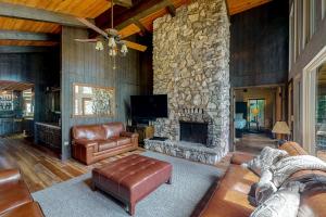 uma sala de estar com lareira de pedra e mobiliário de couro em Twets Lakefront em Bass Lake