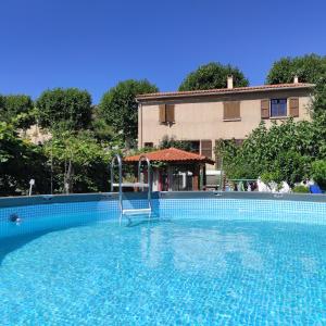 a swimming pool with a chair in front of a house at Villa Aimé in Caunes-Minervois