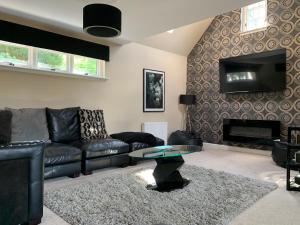 a living room with a black leather couch and a table at Monboddo Townhouse in Auchenblae