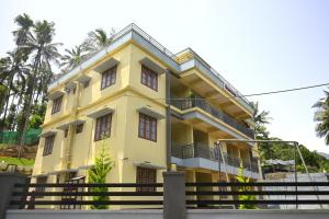 a yellow building with trees in the background at Besrauma Vythiri in Vythiri