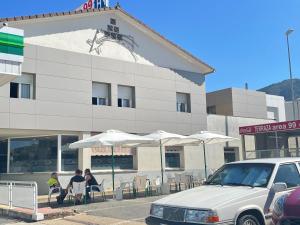 a building with people sitting at tables and umbrellas at Área 99 in Estella