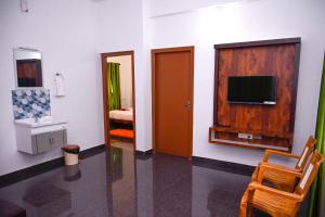 a room with a tv on a wall with a chair at Besrauma Vythiri in Vythiri