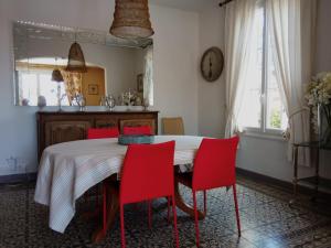 a dining room with a table and red chairs at Jardin de la ciotat 5mn des plages in La Ciotat