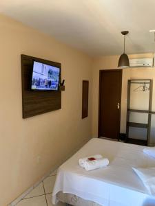 Pousada Beach House في كابو فريو: غرفة نوم مع سرير وتلفزيون على الحائط